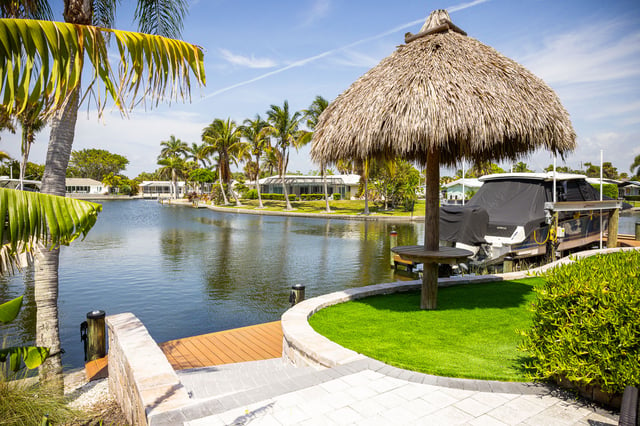 tiki umbrella and artficial turf looking over water 