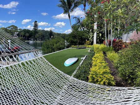 Residential landscape design green lawn and plants hammock near water